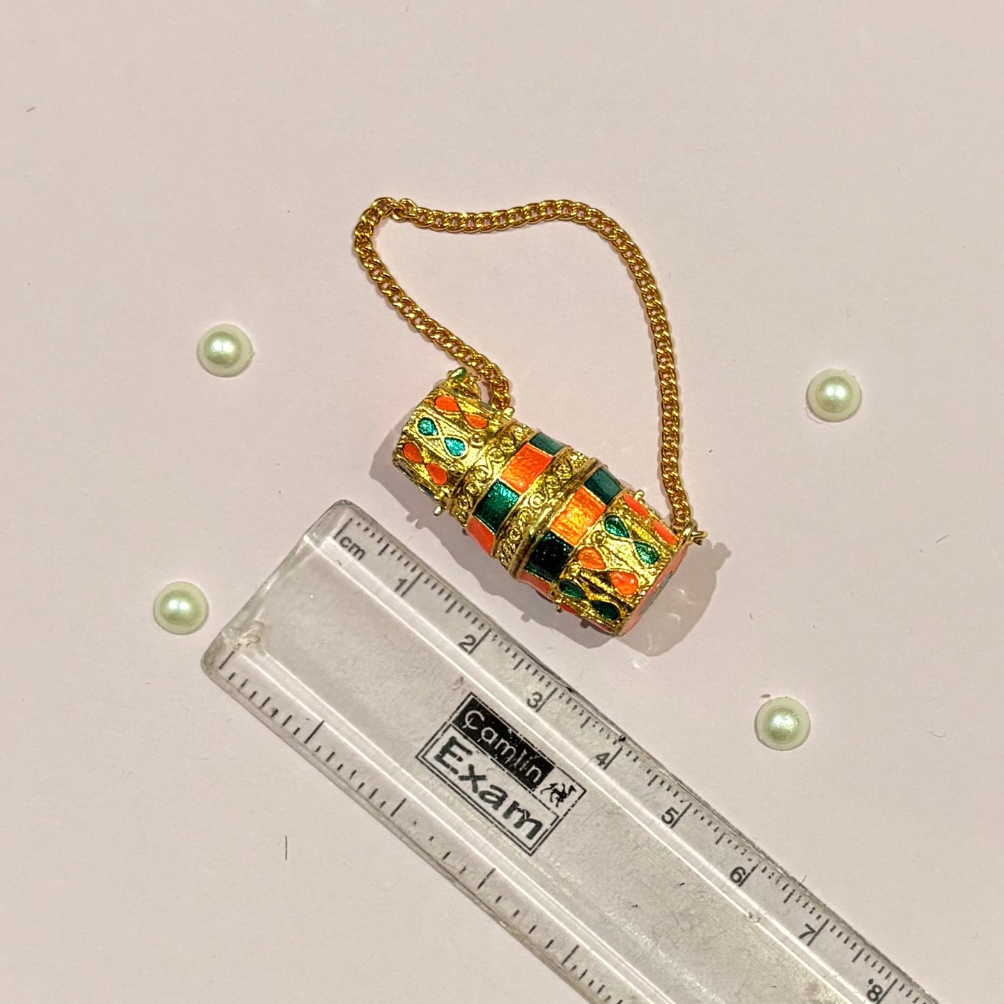 Close-up of the miniature Dholak shringar accessory for Laddu Gopal and Thakur Ji, with intricate gold detailing and colourful enamel work