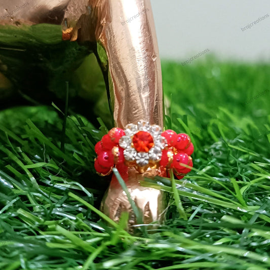 Rose gold high-heeled shoe with red and clear embellishments on grass