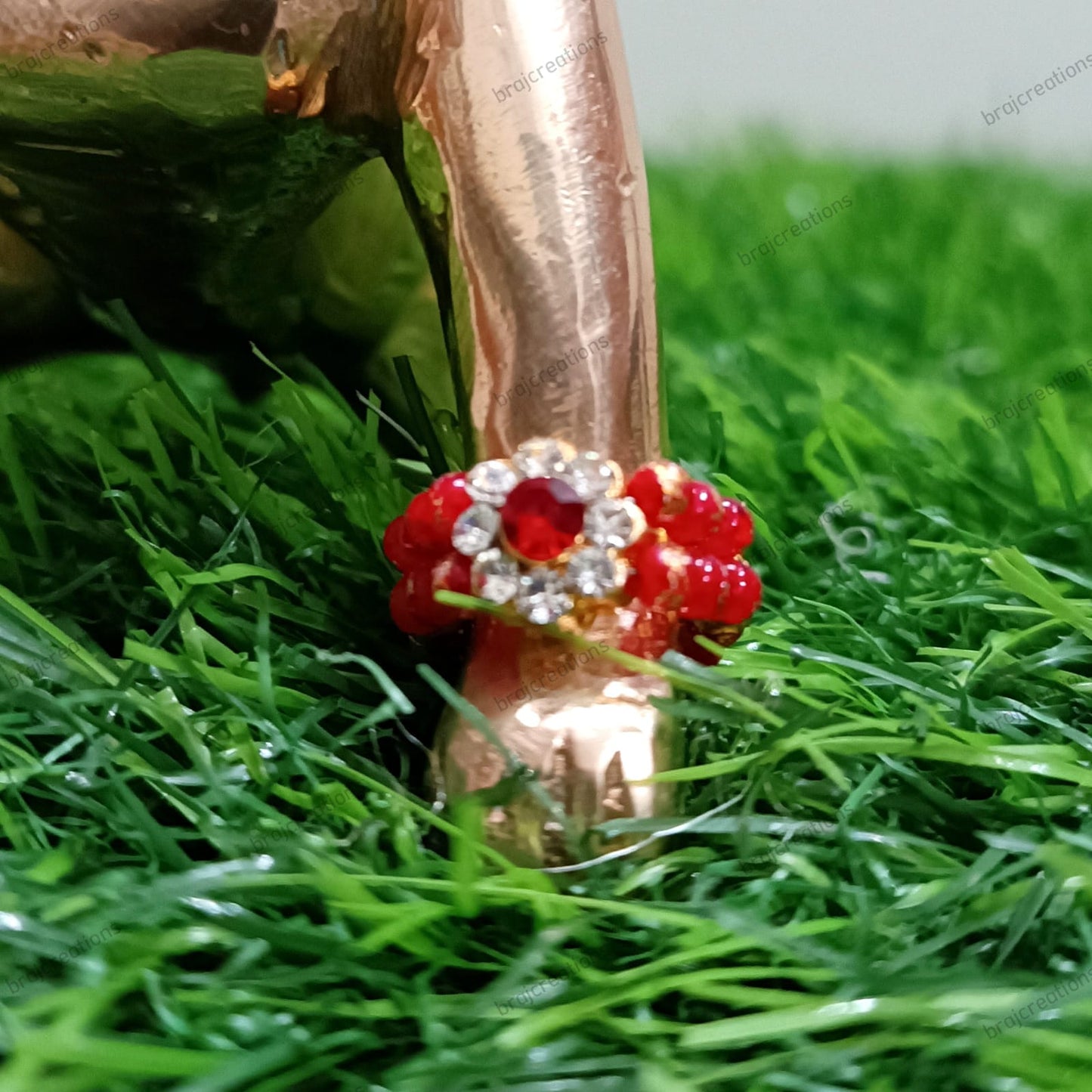 Rose gold ring with red gemstones on a green grass background