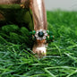 Gold ring with green gemstones on a grass background