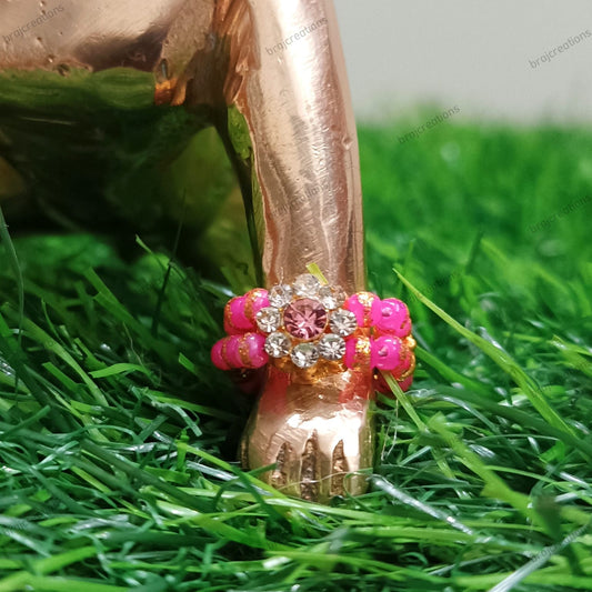 Decorative rose gold ring with pink beads on a green grass background