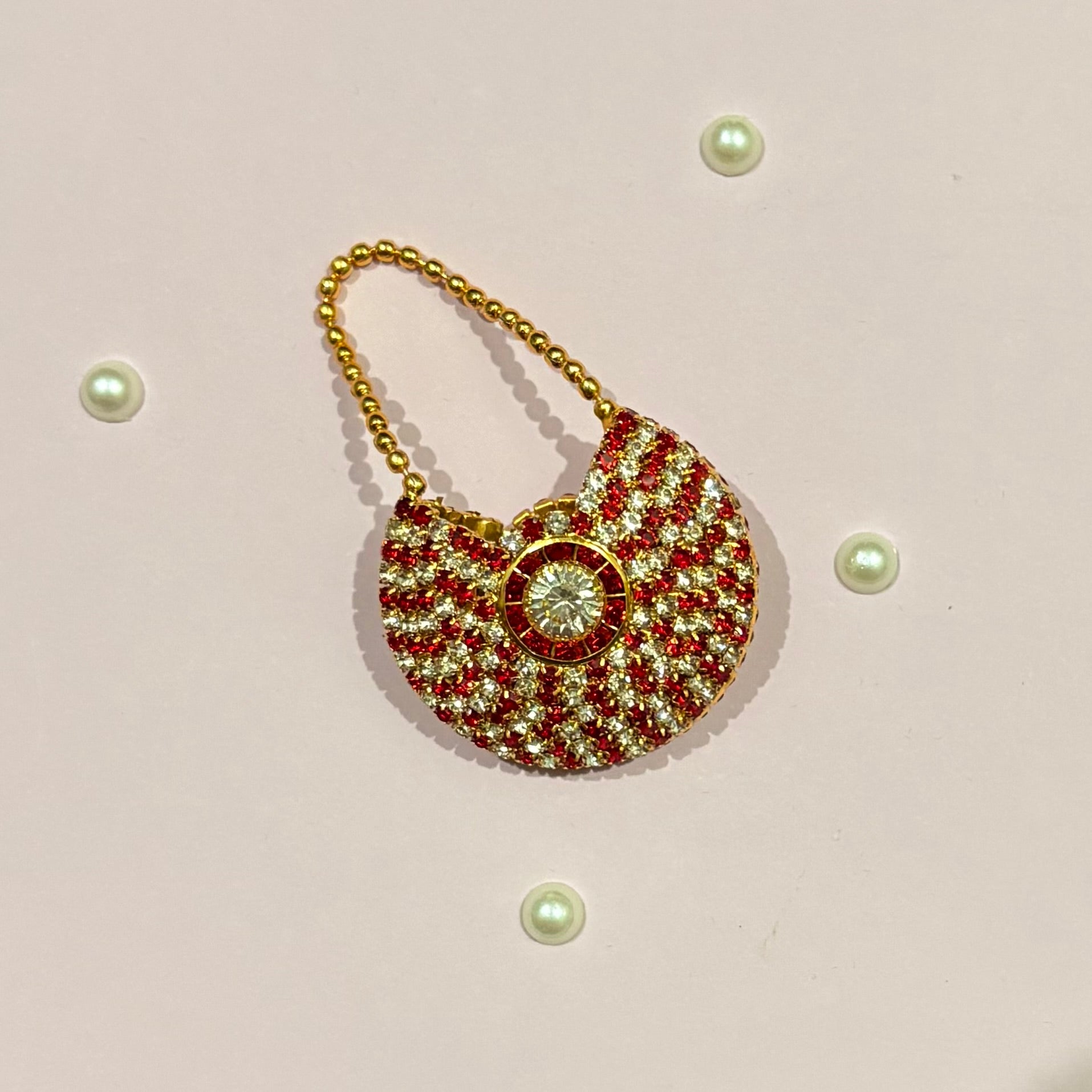 Red AD Moon Shaped Purse, a small gold-tone stone-studded crescent purse to adorn deity idols like Radha Rani and Laddu Gopal